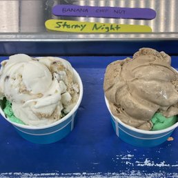 Mint Oreo - Two cups of ice cream with different flavors are placed on a blue surface, with colorful labels above indicating flavors.