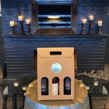 JM Cellars - three bottles of wine in front of a fireplace - Wineries Near Me - Woodinville, Washington JM Cellars - three bottles of wine in front of a fireplace - Wineries Near Me - Woodinville, Washington