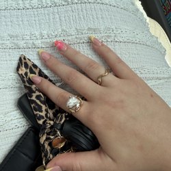 Acrylic almond nails, yellow French tip with pink flower decal.