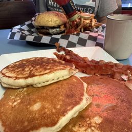 Pancakes with a side of bacon & a burger with fries Pancakes with a side of bacon & a burger with fries