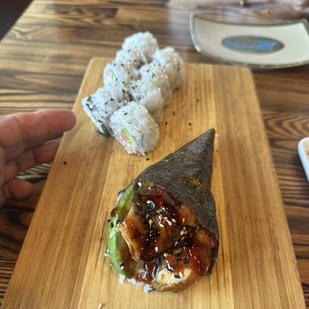 Rock & Roll Sushi - Unagi handroll and California roll on an old wooden dish that was wet - Japanese Near Me - San Leandro, California Rock & Roll Sushi - Unagi handroll and California roll on an old wooden dish that was wet - Japanese Near Me - San Leandro, California