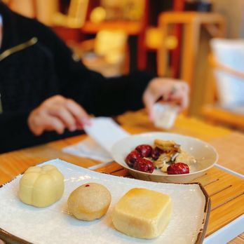 VAN CHA - a woman sitting at a table with a plate of food - Tea Rooms Near Me - Vancouver, British Columbia VAN CHA - a woman sitting at a table with a plate of food - Tea Rooms Near Me - Vancouver, British Columbia