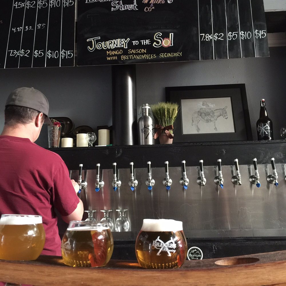 Relentless Brewing - View of the tap list with brewer James in the background. - Breweries Near Me - Temecula, California Relentless Brewing - View of the tap list with brewer James in the background. - Breweries Near Me - Temecula, California