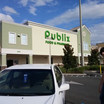 Publix Super Markets - a man standing in front of a white car - Grocery Near Me - Lakeland, Florida