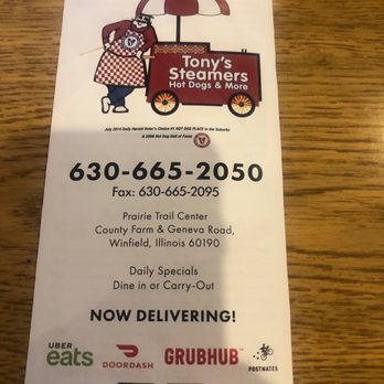 Steamers - Menu - A printed menu for Tony's Steamers hot dog stand features a cartoon illustration of a man with a beard, apron, and umbrella, standing next to a food cart. The menu includes the business name, phone number, fax number, and address in Winfield, Illinois. It highlights daily specials, dine-in or carry-out options, and delivery services via Uber Eats, DoorDash, Grubhub, and Postmates. The flyer also promotes online ordering and pickup options. - Hot Dogs Near Me - Winfield, Illinois