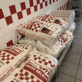 Five Guys - a row of bags of pizza sitting on a bench - Burgers Near Me - Watchung, New Jersey