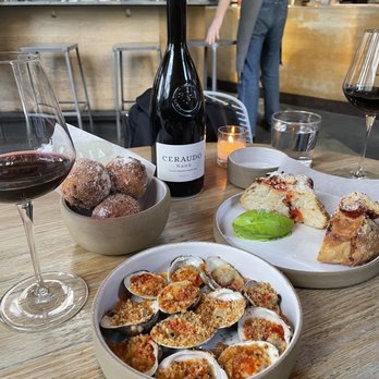 Lilia - Back left: Cacio e Pepe Fritelle, back right: cherry tomato focaccia, front: Grilled Clams - Italian Near Me - Brooklyn, New York Lilia - Back left: Cacio e Pepe Fritelle, back right: cherry tomato focaccia, front: Grilled Clams - Italian Near Me - Brooklyn, New York