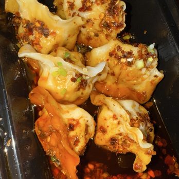 Bryan's Dumpling House - Six dumplings with chili oil, chopped green onions, and spices are in a black container, likely from a dumpling restaurant. - Dim Sum Near Me - Denver, Colorado