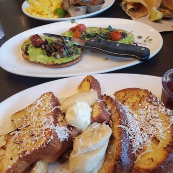 Beach Plum Kitchen - Cococonut-almond crusted French toast with avocado toast and carnitas & eggs in the background. - New American Near Me - Carlsbad, California