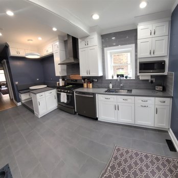 Samanco Construction - a kitchen with white cabinets and black appliances - General Contractors Near Me