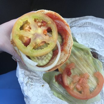 Wendy's - a person holding a sandwich with tomatoes and lettuce - Fast Food Near Me - Indian Trail, North Carolina