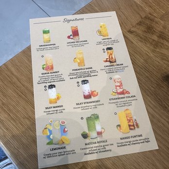 Teaspoon - Signature Menu - A printed menu displays a selection of signature beverages, each with a colorful image and detailed description, on a wooden table. - Bubble Tea Near Me - Mansfield, Texas