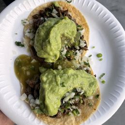Two tacos de asada con todo.  TJ style with guacamole & green sauce.