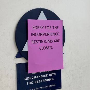 Marshalls - A blue and white sign on a wall informs customers to bring merchandise into the restrooms. A pink notice overlays the sign, stating restrooms are closed. - Department Stores Near Me - Campbell, California