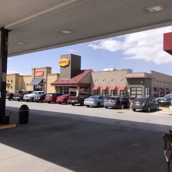 Flying J - Worst flying J in 8000 miles of cross country travel - The image shows a Denny's restaurant situated across a parking lot from a gas station in El Paso, Texas. Several cars are parked in front of the restaurant, and a person is seen near one of the vehicles. The sky is partly cloudy, and the scene is viewed from beneath a gas station canopy, with fuel pumps visible on the sides. The overall setting indicates a typical roadside stop with a recognizable fast-food chain and fueling station. - Gas Stations Near Me - El Paso, Texas