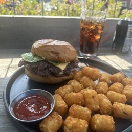 Smashburger with tots and a diet Pepsi sitting outside on the patio