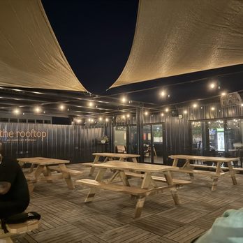 Downtown By Chef Jay Pisculli - Looking from street side to building aid, featuring the picnic tables coving most of the roof and the enclosed  bar - Lounges Near Me - Binghamton, New York