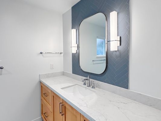 Stone & Wave Haven - This remodel was designed as a modern spa retreat defined by contrast, texture, and clarity. Off-white marble-look tile establishes a clean, neutral foundation, while blue herringbone surfaces introduce bold visual rhythm at the shower and vanity. A natural wood vanity adds warmth, grounding the palette and balancing the cool tones. Stone & Wave Haven - This remodel was designed as a modern spa retreat defined by contrast, texture, and clarity. Off-white marble-look tile establishes a clean, neutral foundation, while blue herringbone surfaces introduce bold visual rhythm at the shower and vanity. A natural wood vanity adds warmth, grounding the palette and balancing the cool tones.