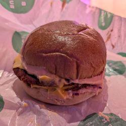 Beer and Burger - Plant-based burger with regular cheese (covered in chopped onion, a sauce, and has four pickle slices)
