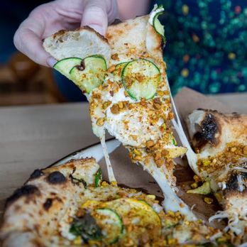 Indaco - a person taking a slice of pizza - Italian Near Me - Charlotte, North Carolina Indaco - a person taking a slice of pizza - Italian Near Me - Charlotte, North Carolina