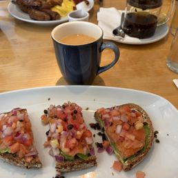 Avocado Toast with smoked salmon, coffee, and tea in the background Avocado Toast with smoked salmon, coffee, and tea in the background