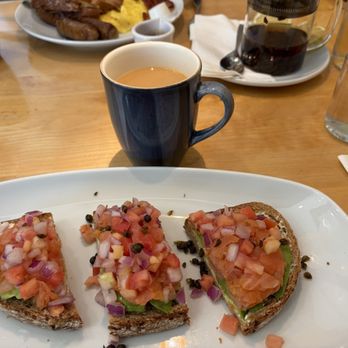 Yolk - South Loop - Avocado Toast with smoked salmon, coffee, and tea in the background - Breakfast & Brunch Near Me - Chicago, Illinois Yolk - South Loop - Avocado Toast with smoked salmon, coffee, and tea in the background - Breakfast & Brunch Near Me - Chicago, Illinois