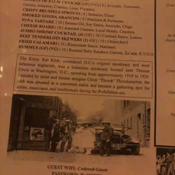 CODE RED - The image shows a menu page with food items such as cheese bruschetta, ceviche, and shrimp cocktail, along with descriptions and prices. Below the menu, there is a historical black-and-white photo of people standing on a street with a vintage car. The Wi-Fi details are provided at the bottom, indicating guest Wi-Fi network and password. - Cocktail Bars Near Me - Washington, DC, District of Columbia
