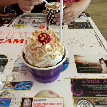 Rizuto's - a woman sitting at a table with an ice cream sundae - Ice Cream & Frozen Yogurt Near Me - Colorado Springs, Colorado Rizuto's - a woman sitting at a table with an ice cream sundae - Ice Cream & Frozen Yogurt Near Me - Colorado Springs, Colorado