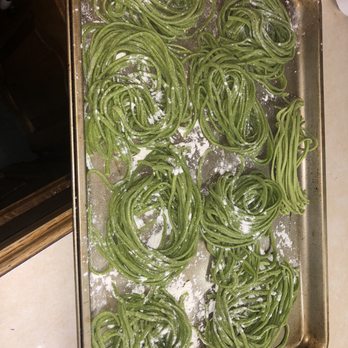 Costco - Several green pasta nests are placed on a metal baking sheet, dusted with flour, and arranged in a somewhat orderly fashion. The pasta appears freshly made, with a vibrant green color, possibly from spinach or herbs. The sheet is on a kitchen countertop, indicating food preparation or cooking process. - Wholesale Stores Near Me - Mount Laurel, New Jersey