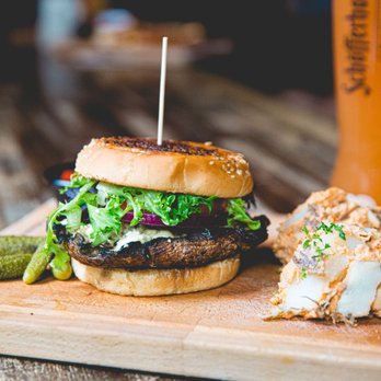 Berliner Pub - a burger and a pickle on a cutting board - German Near Me - Renton, Washington