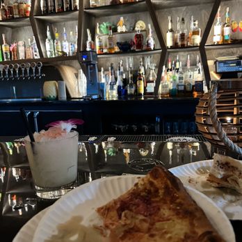 The Hello Hi - Pizza from the back with a drink called: HUMUHUMUNUKUNUKUAPUA'A both delicious - Cocktail Bars Near Me - Sioux Falls, South Dakota