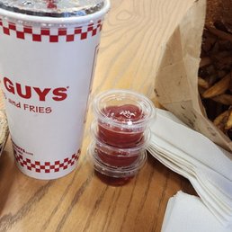 a table with a bag of peanuts, a cup of ketchup, and a bag of peanuts