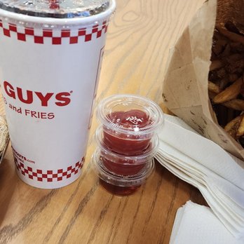 Five Guys - a table with a bag of peanuts, a cup of ketchup, and a bag of peanuts - Burgers Near Me - Chantilly, Virginia