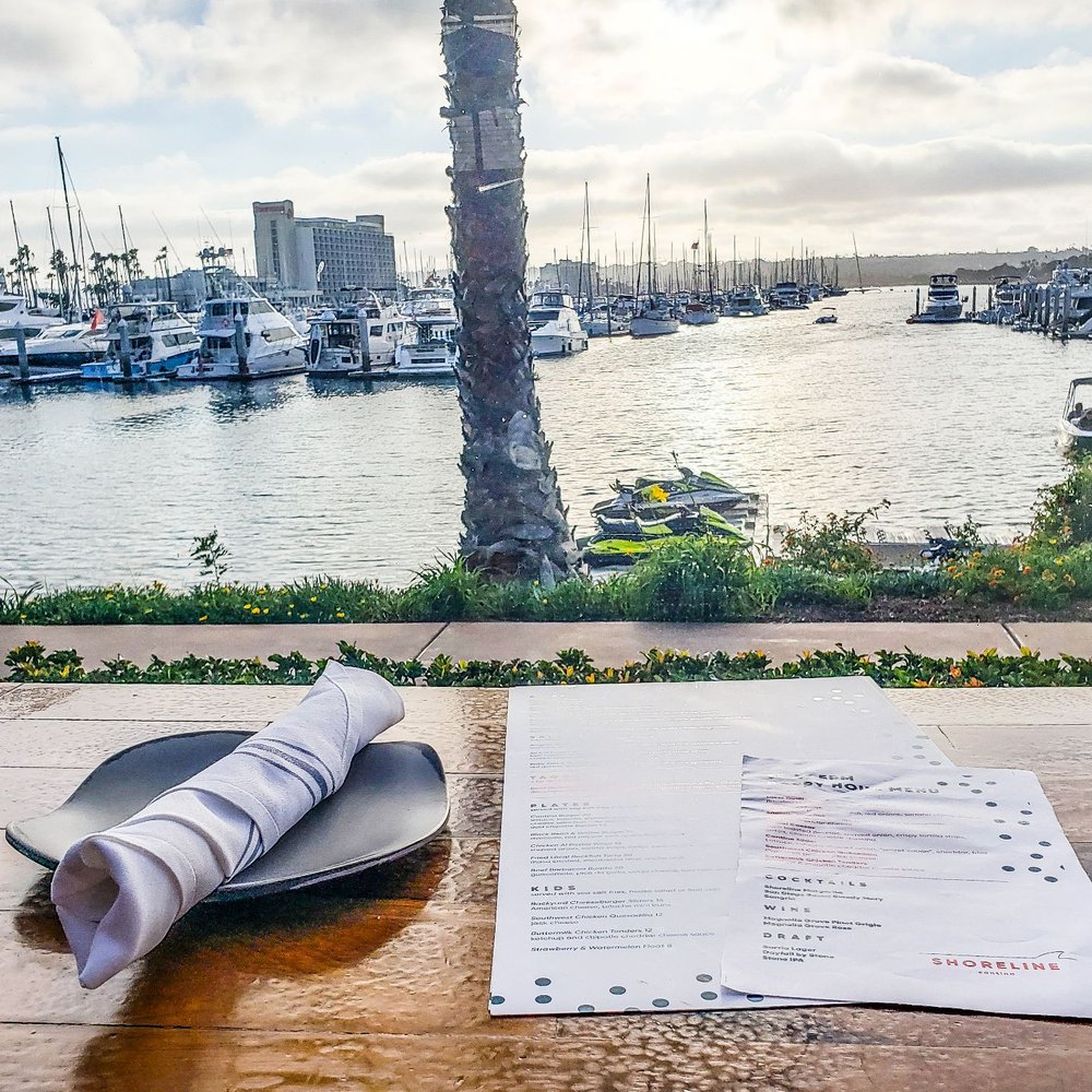 Shoreline - a table with a menu and a view of a marina - New American Near Me - San Diego, California Shoreline - a table with a menu and a view of a marina - New American Near Me - San Diego, California
