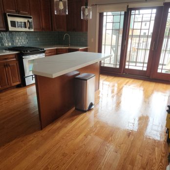 Rapid Response Restoration - A kitchen features wooden cabinets, a white countertop island, and sliding glass doors with metal bars leading to a balcony. - Damage Restoration Near Me - Chicago, Illinois