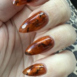 Almond acrylic with gold foil and black accents under sheer brown lacquer Almond acrylic with gold foil and black accents under sheer brown lacquer