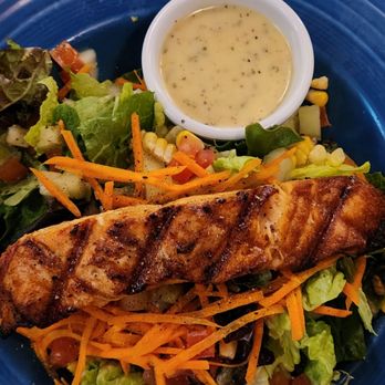 The Kill Devil Grill - Grilled Salmon Salad ($18) with a big salmon fillet over mixed greens, cut corn, grape tomatoes, carrots, and cukes - American Near Me - Kill Devil Hills, North Carolina