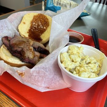 5 Thumbs BBQ - Sliced Brisket and mustard potato salad - A meal featuring a sliced brisket sandwich with barbecue sauce, potato salad, and a snack bag on a red tray at a restaurant. - Barbeque Near Me - Indianapolis, Indiana