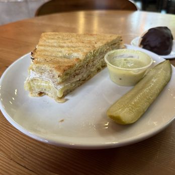 Crema Coffee + Bakery - Turkey with brie Panini, toasted, with a delicious sauce and pickle. Chocolate dipped coconut, macaroon lurking in the background. - Bakeries Near Me - Portland, Oregon Crema Coffee + Bakery - Turkey with brie Panini, toasted, with a delicious sauce and pickle. Chocolate dipped coconut, macaroon lurking in the background. - Bakeries Near Me - Portland, Oregon