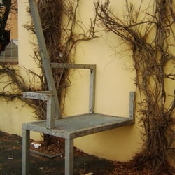 Humor-Kirche - Sitzgelegenheit aus Stahl an der Kirchenaußenwand