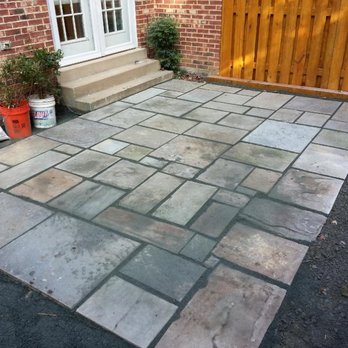 Next Level Landscaping & Home Design - a patio with a brick wall - Roofing Near Me Next Level Landscaping & Home Design - a patio with a brick wall - Roofing Near Me
