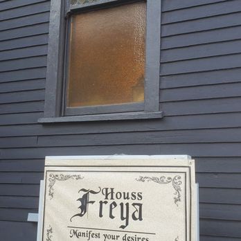 Houss Freya - A sign for Houss Freya, a spiritual shop, is positioned outside a building with a stained glass window and dark siding. - Spiritual Shop Near Me - Montclair, New Jersey