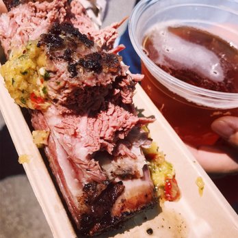 Carnal - a person holding a plate of food and a cup of beer - Food Stands Near Me - Brooklyn, New York