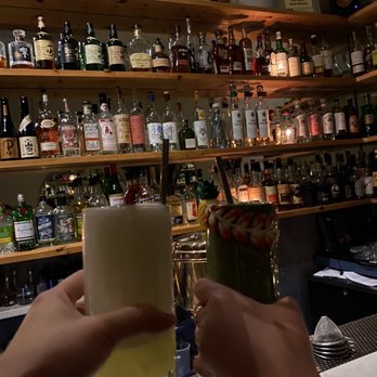 The Hidden Pearl - a person holding a glass of alcohol - Cocktail Bars Near Me - Brooklyn, New York
