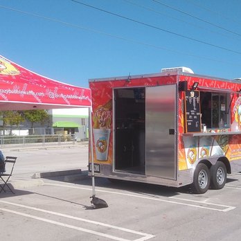Crazy Bubble Waffle - A red bubble waffle food truck is parked in a parking lot, with a red canopy tent nearby where customers are seated at tables. - Desserts Near Me - Miami, Florida
