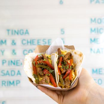 Tacocina - a hand holding a taco in front of a menu - Tacos Near Me - Brooklyn, New York Tacocina - a hand holding a taco in front of a menu - Tacos Near Me - Brooklyn, New York