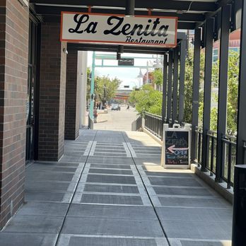 La Zenita - The image shows the exterior of La Zenita Restaurant with a sign hanging above the sidewalk and a chalkboard menu on the side. - Mexican Near Me - Albuquerque, New Mexico