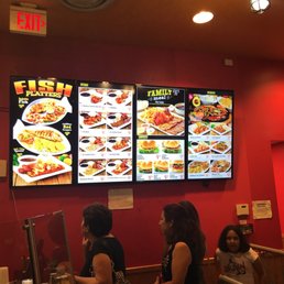 a group of people standing in front of a menu a group of people standing in front of a menu