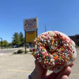 a hand holding a donut with sprinkles a hand holding a donut with sprinkles