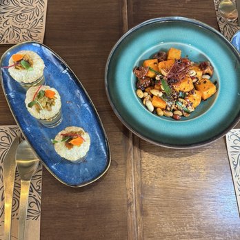 Tamashaa - Bori Chili Silken Tofu & Pan Puri Shots - A photo shows three small servings of Indian dishes on a blue oval plate and a larger bowl with roasted vegetables and grains, set on a wooden table. - Indian Near Me - Washington, DC, District of Columbia